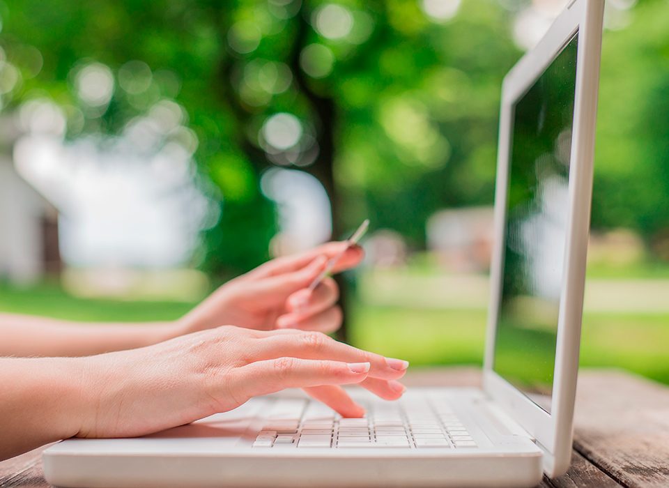 mãos de uma mulher digitando em uma notebook